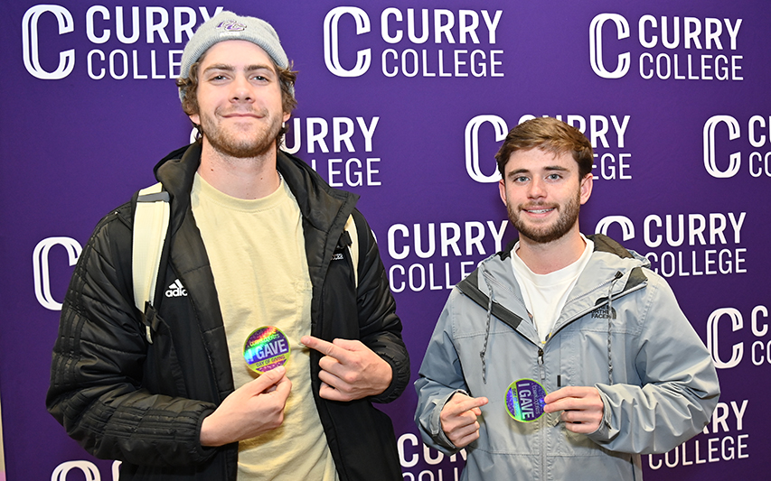 Two students pose with "I Gave" stickers at Curry's Day of Giving