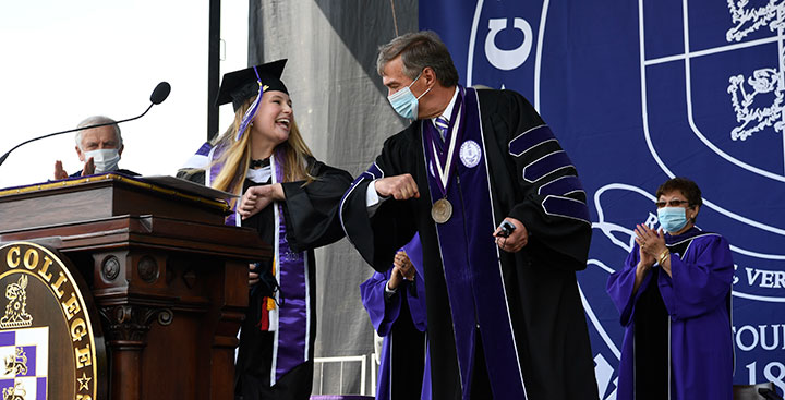Miranda Trieble ’20 bumps elbows with President Quigley, after singing the National Anthem at the Commencement Exercises honoring the Class of 2020 on May 22, 2021.