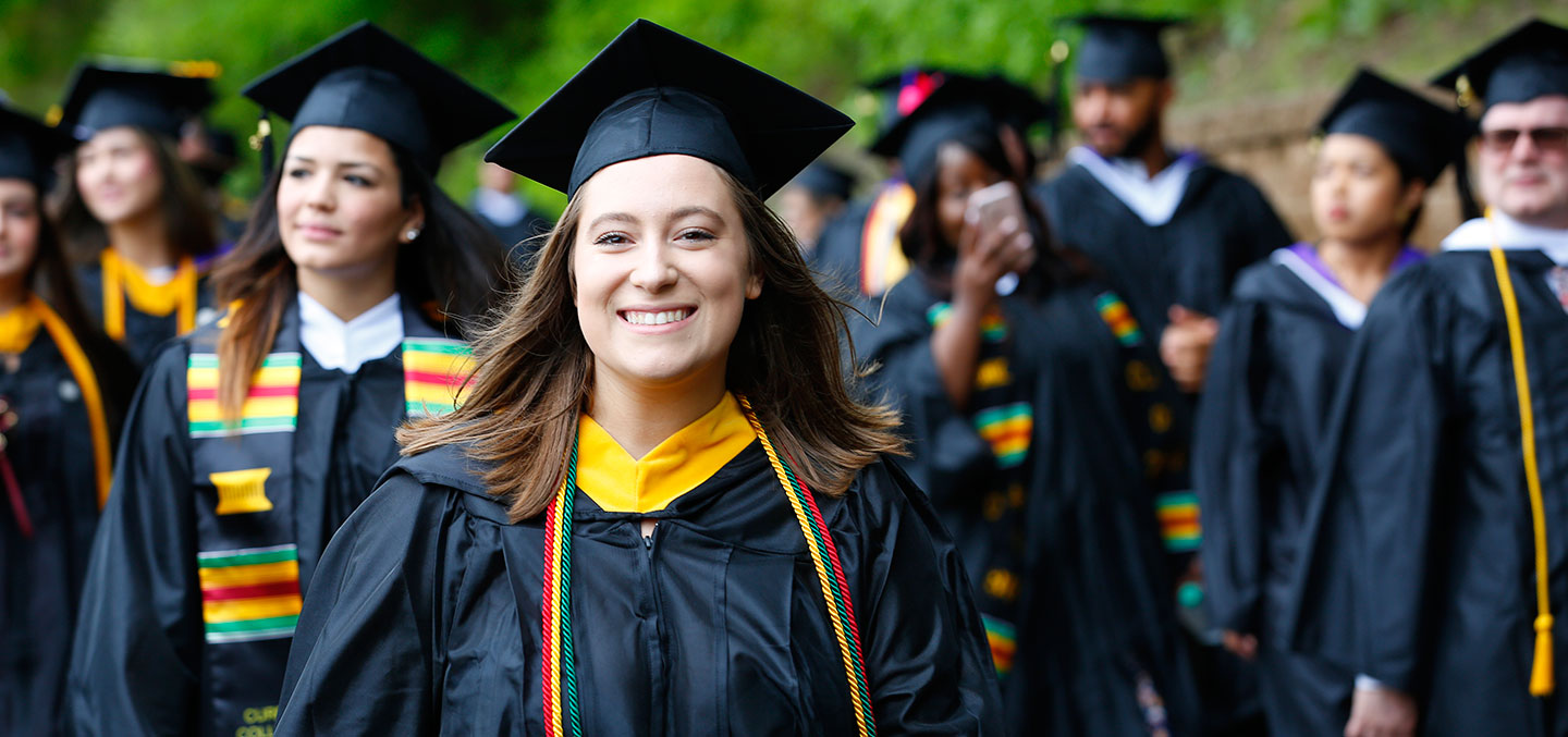 A Curry College student walks on Commencement representing the Curry Fund