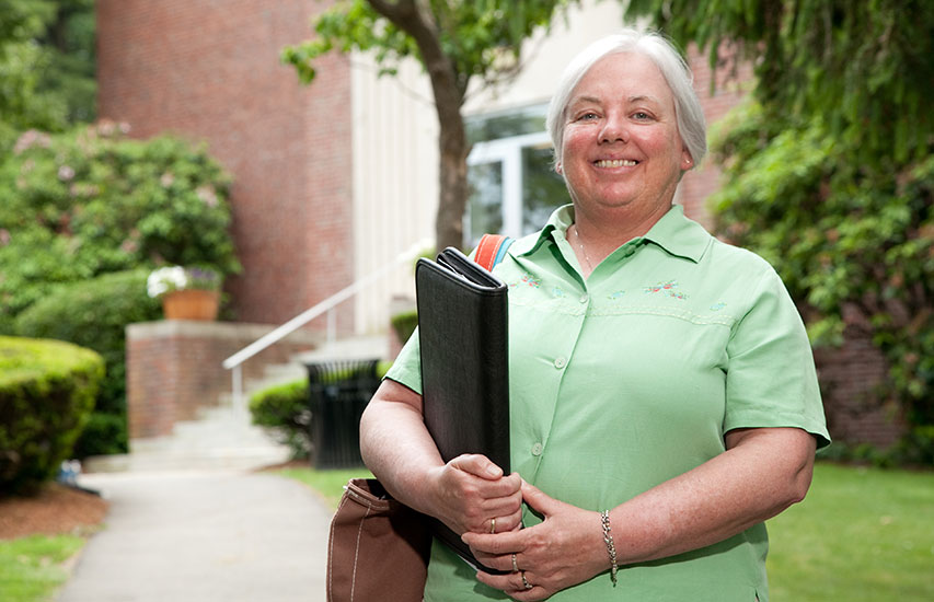 A Curry College Master of Science in Nursing Degree in Nurse Administration student poses for a photo on campus