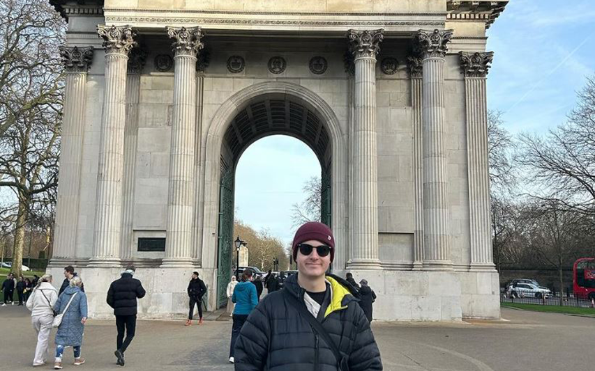 Curry College study abroad student poses in front of an historic arch