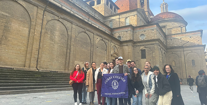 Students pose for a picture with a Curry College sign in Florence
