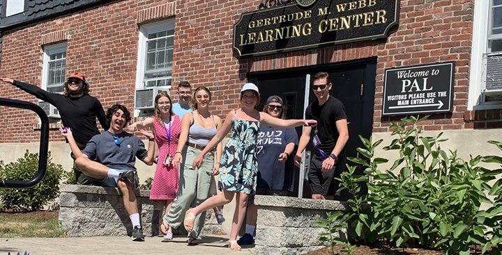 Curry College Summer PAL students laugh and smile for a picture in front of the Webb Learning Center