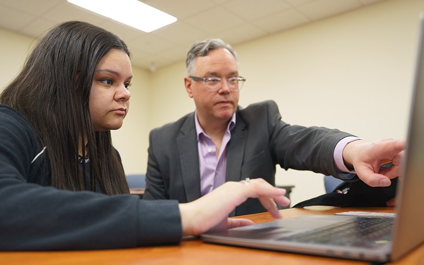 Student in class pursuing a Marketing major with her professor at Curry College