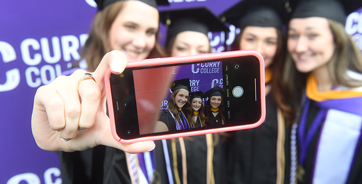 Curry College students smiling for a selfie at Graduation