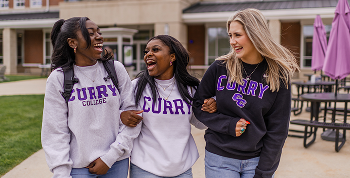 Curry College students laugh together while walking on campus