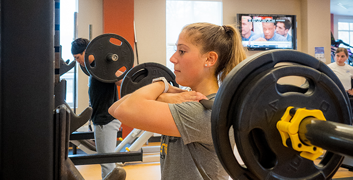 A student lifts weights in the fitness center