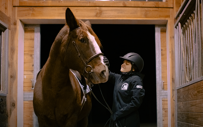 Curry College Equestrian Club member pets her horse