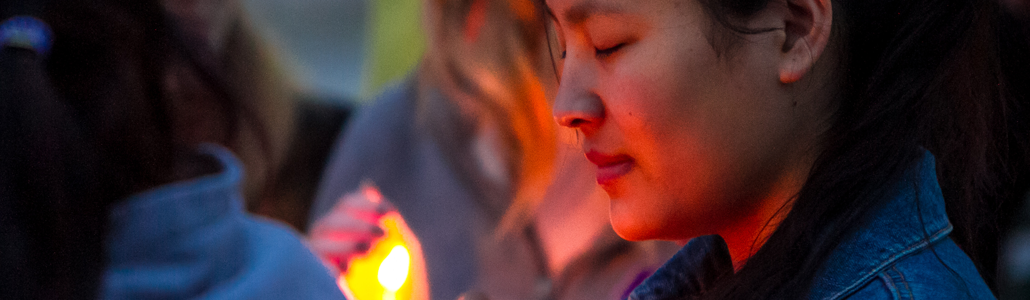 A student attends a candlelight vigil on campus